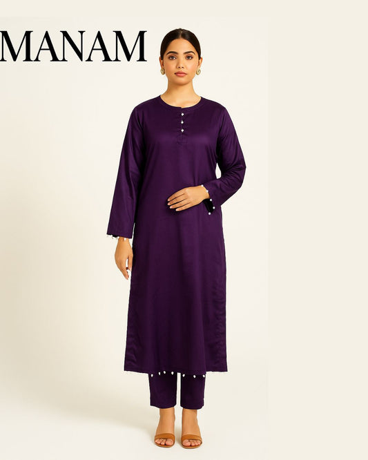 Woman wearing a casual pearl detailed  deep plum shirt with trouser  a white background, branded 'Manam'.