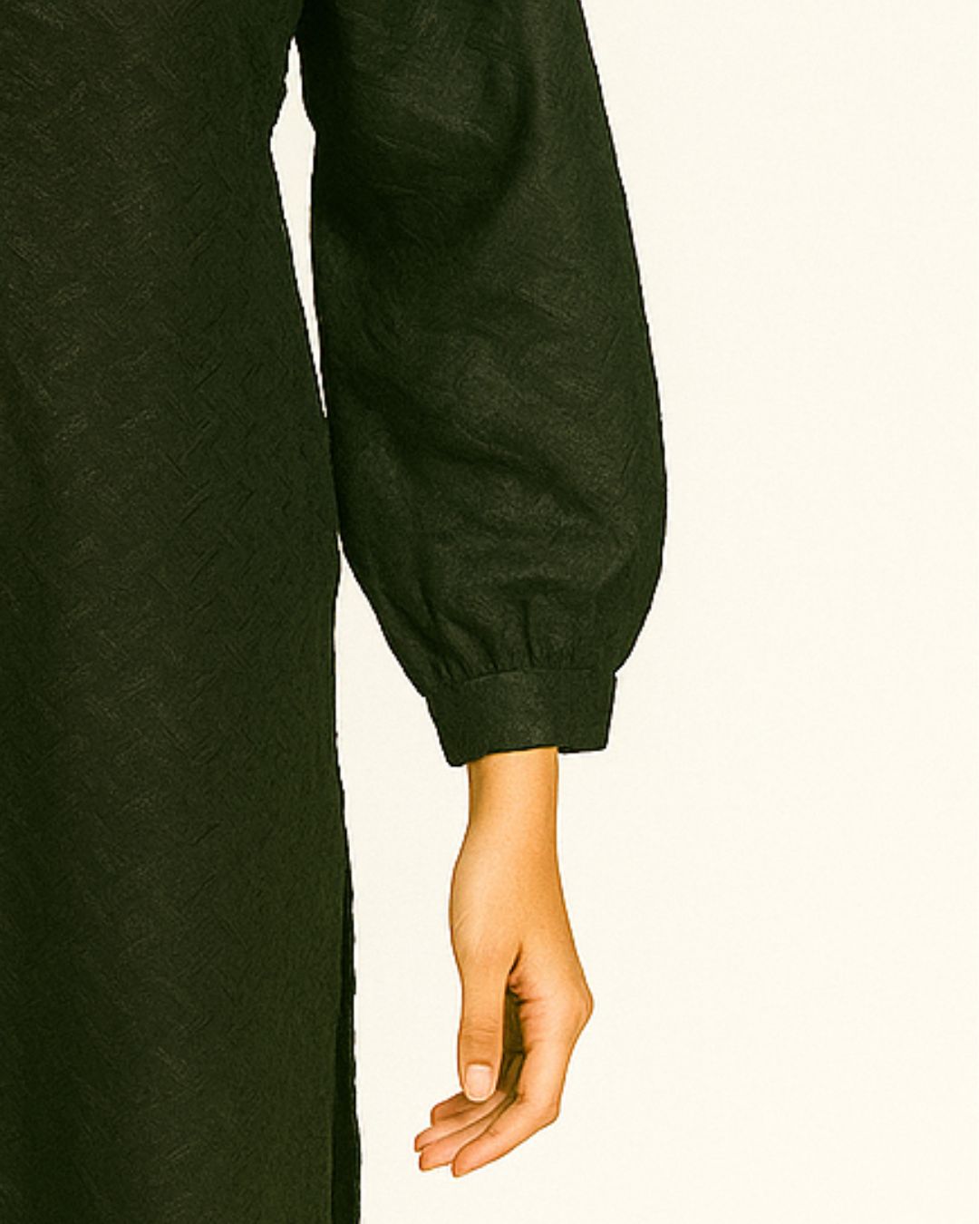 Close-up of a person wearing a black chikankari long-sleeve kurta with a plain background