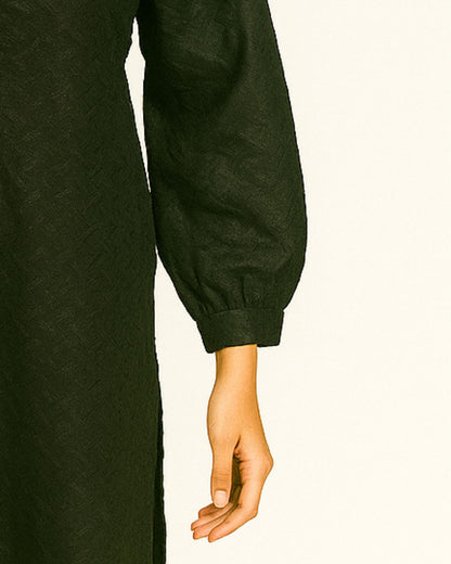 Close-up of a person wearing a black chikankari long-sleeve kurta with a plain background