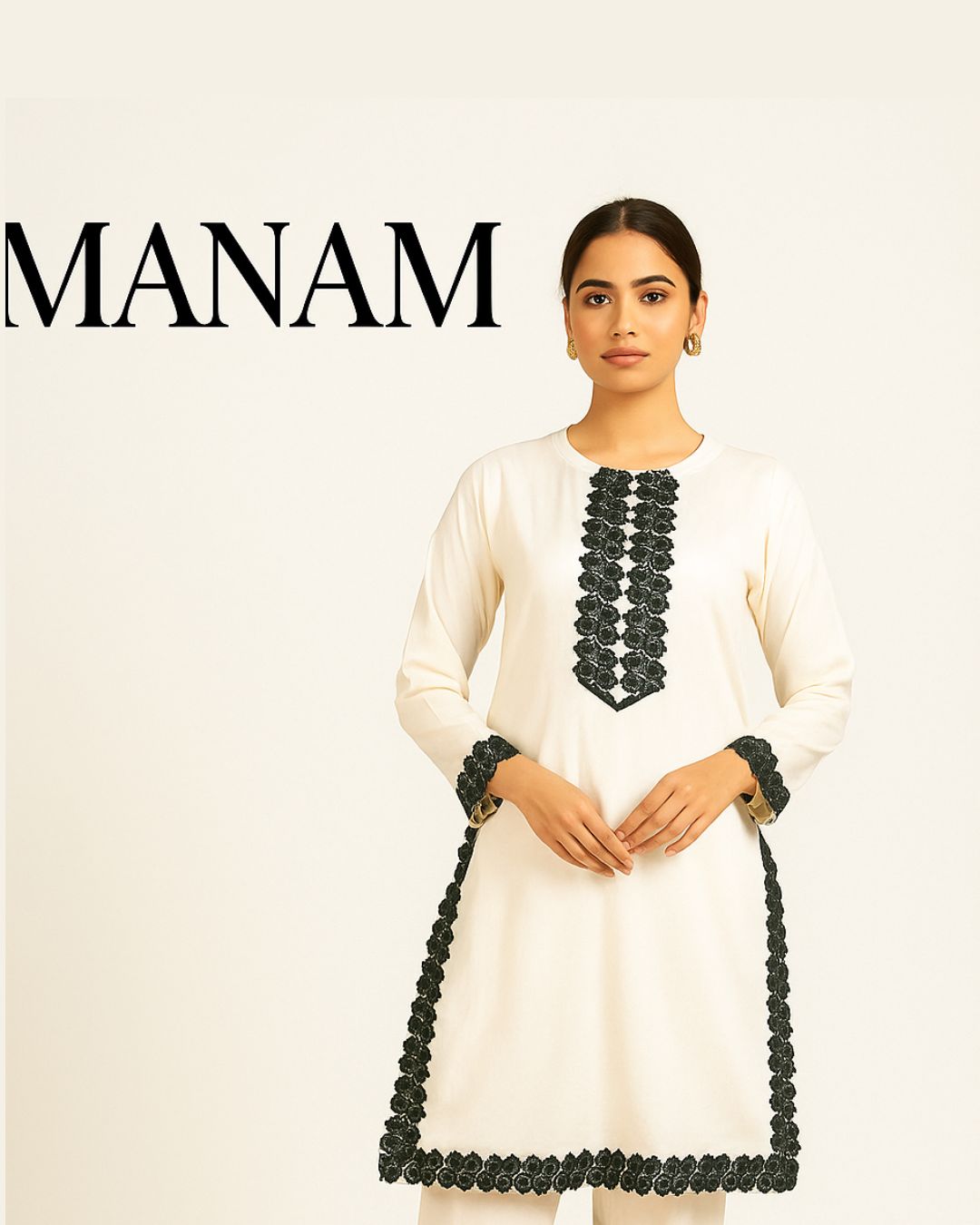 Woman wearing a white dress with black  lace embroidery, with 'MANAM' branding above.